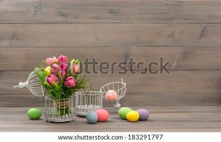 tulip flowers and colorful easter eggs over wooden background