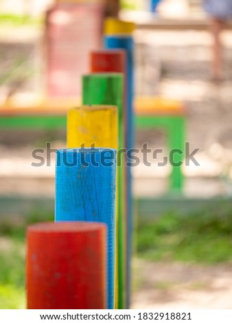 Red, Blue, Yellow and Green Colored Poles in Line Shot with Shallow Depth of Field