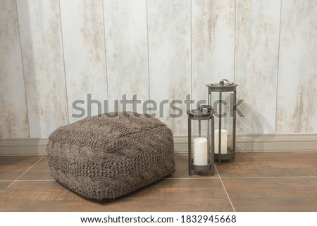 Knitted pouffe and old wooden lanterns on ceramic floor Royalty-Free Stock Photo #1832945668