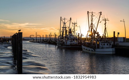 Colourful sunset at the small harbour with crab boats in Wremen near Cuxhaven, Germany Royalty-Free Stock Photo #1832954983