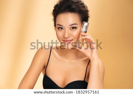 Woman with liquid foundation. Photo of asian woman with perfect makeup on beige background. Beauty concept