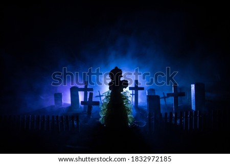 Girl walking alone in the cemetery at night. Dark toned foggy background. Horror Halloween concept. Creative artwork decoration