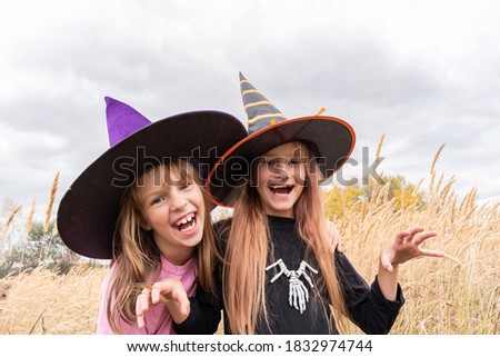 Girlfriends in halloween costumes are playing. Open space. Mysterious setting Child dressed as a devil and a witch