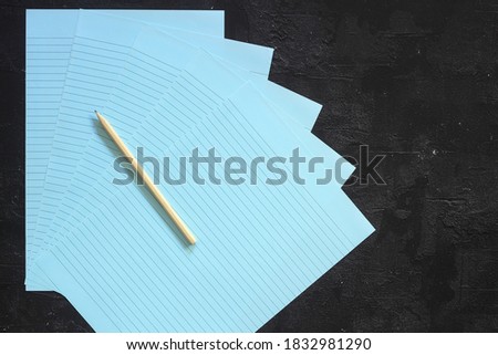 Flat lay, top view, blue sheet and pencil on a gray textured background. Rays of light from the side