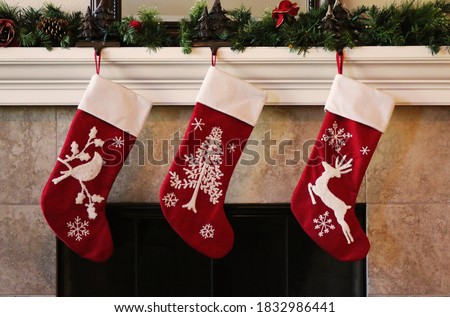 Three red christmas stockings on fireplace mantle Royalty-Free Stock Photo #1832986441
