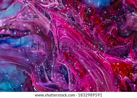 Resin art paint with pink, blue and red colors. Fluid backdrop with splashes and swirls. Abstract frozen artwork with splatter inks. Bright colors mixes on macrophotography picture.