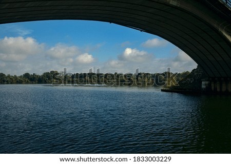 Shore of a lake in the distance framed by the arch of a bridge