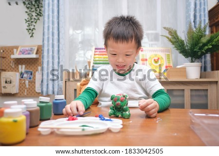 Cute happy little Asian 3 - 4 years old toddler boy child  painting color on DIY plaster painting toy, 3D plaster statue indoor at home, Creative play for kids and toddlers concept - Selective focus