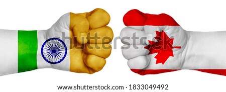 The concept of the struggle of peoples. Two hands are clenched into fists and are located opposite each other. Hands painted in the colors of the flags of the countries. Canada vs India