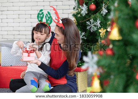 mother showing or giving the gift box for cute daughter in christmas day at home