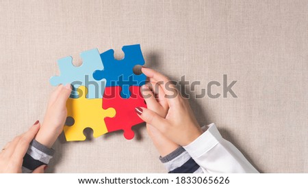 Top view banner - World autism awareness day, understanding & love concept, a beautiful mother holding hands of an autistic child with symbol colored puzzle. ASD, April 2, Family, Together, Support.
