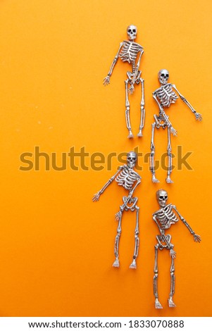 Dancing skeletons on the orange background. Halloween skeleton dancer. Modern Halloween or Day of the Dead concept.