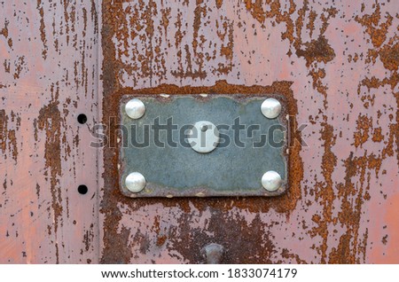 Rusty sheet of metal with a rectangular plate. Red metal background with peeling paint. Creative abstract background. Without anyone