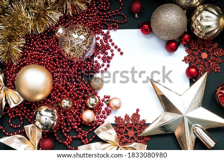 Golden Merry Christmas and Happy New Year Decoration. Red and gold Bauble on Christmas black background. Winter time. Snowflake. Space for text. White square frame. Flat lay.