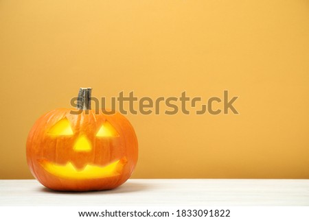 Scary jack o'lantern pumpkin on yellow background, space for text. Halloween decor