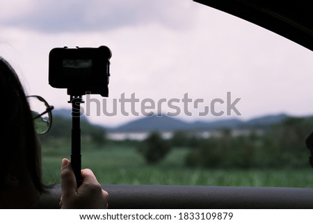 Woman holding Action cam in car to take photo of mountain 
