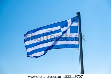 Greece sign symbol. Greek flag on flagpole waving in the wind. Blue sky, sunny spring day in Athens.
