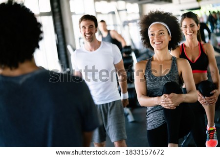Beautiful fit people exercising together in gym