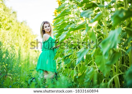 blond european girl in a green dress  on nature with sunflowers
