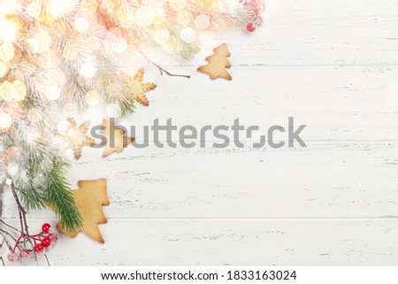 Christmas greeting card with fir tree and gingerbread cookies on wooden background. Top view flat lay with space for your xmas greetings