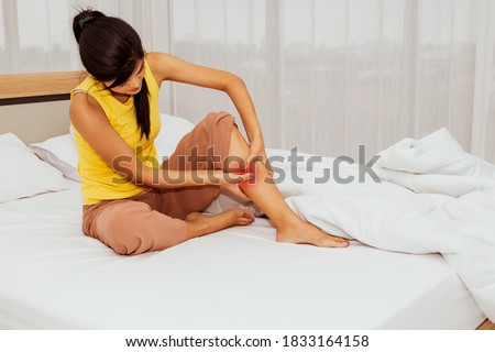 Concept health care and first aid : The woman sat with acute thigh muscle pain from cramping while she slept in bed, and she was doing a massage to relax her muscles : Selective Focus Royalty-Free Stock Photo #1833164158
