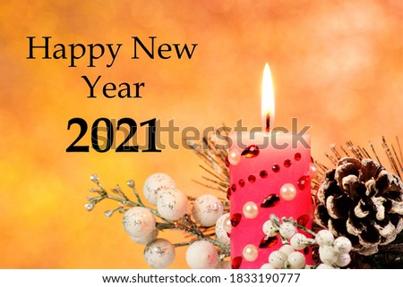 Happy new year to 2021. Text inscription on the background of the glitter of bokeh lights, a bright holiday candle on the background of an elegant snow-covered fir branch with a cone.