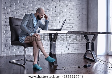 quarantined work concept, a man works at home on a computer in his underpants, funny work coronavirus pandemic meme Royalty-Free Stock Photo #1833197746