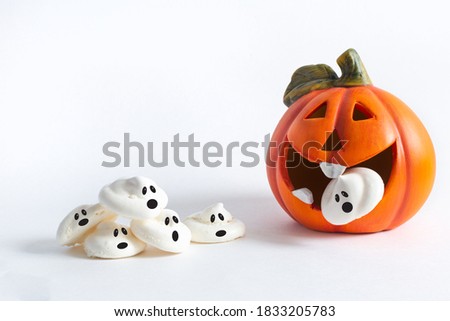 An orange cheerful pumpkin eats a screaming meringue ghost, next to a company of frightened ghosts on a white background. Halloween, All Saints Day, traditional autumn holiday.Trick or treat.Postcard.