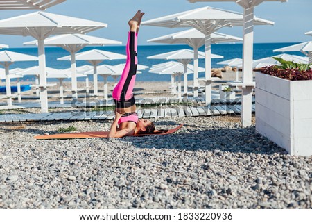 Beautiful brunette woman in sportswear sports gymnastics fitness yoga on the beach by the sea