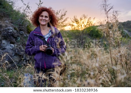 Tourist lady with camera at sunset on an evening hike