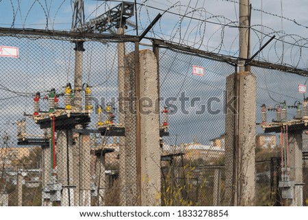 An electrical substation behind a barbed wire fence.