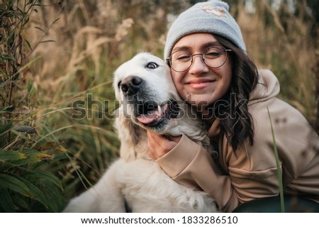 brunette girl in glasses with white golden retriever in the field