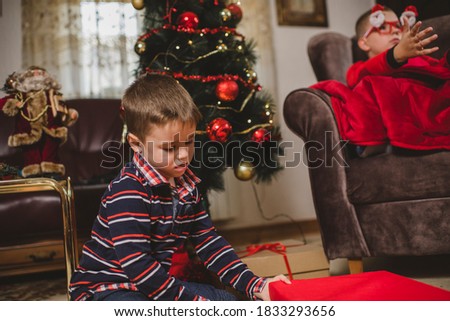 Cute boys opening Christmas gifts and expressing excitement and joy