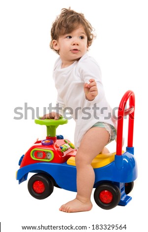 Toddler boy in a car toy looking back isolated on white background