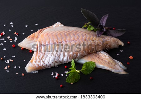 Healthy Food concept raw fillets Alaska Pollock, Black Cod on black slate stone board with copy space 