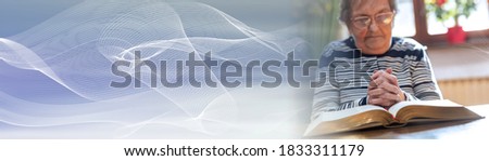 Elderly woman praying with his hands over the bible; panoramic banner