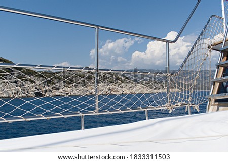 metal deck railing with rope safety mesh on sea sailboat on sea coast background Royalty-Free Stock Photo #1833311503