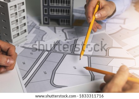 urban planning - people discussing about territory building plots on cadastral map for apartment building construction Royalty-Free Stock Photo #1833311716