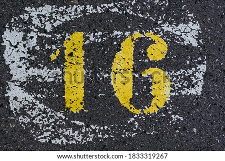 Number sixteen painted white on asphalt - number background