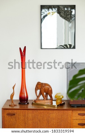 Vintage composition on the wooden cabinet with retro red vase, vinyl recorder, mirror and elegant personal accessories. Template.