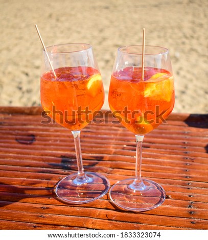 Chilled cocktails, aperol spritz, sitting on the bamboo table.  Slice of fruit, olive and ice. Summer background. Tropical landscape.