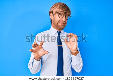 Young blond man wearing business clothes and glasses disgusted expression, displeased and fearful doing disgust face because aversion reaction. with hands raised 
