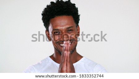 Happy charismatic handsome black guy smiling to camera giving faith sign with hands, feeling compassionate