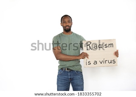 Racism is a virus. Young man protesting with sign isolated on white studio background. Activism, active social position, protest, actual problems. Meeting against human rights, abusing, racism.