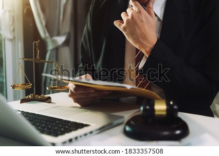 Justice and law concept.Male judge in a courtroom with the gavel, working with, computer and  docking keyboard, eyeglasses, on table 
