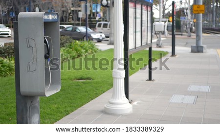 Retro coin-operated payphone station for emergency call on street, California USA. Public analog pay phone booth. Outdated technology for connection and telecommunication service. Cell handset on box. Royalty-Free Stock Photo #1833389329
