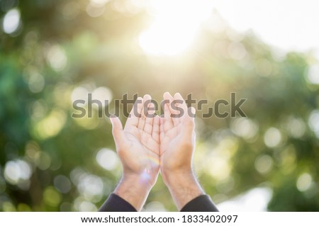 Praying male hands for hope stretch into the sky on nature background with sun light. Religion and belief concept.