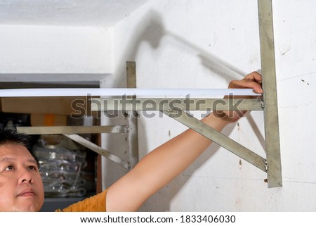 A worker is measuring the length of an iron frame with a tape measure