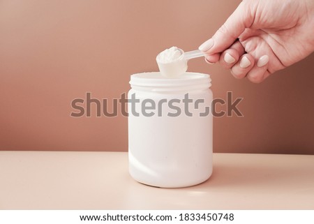 hand holding scoop of fish collagen. collagen peptides in container or jar. powder for mixing drink. Healthcare supplement concept. collagen for skin and joints . Royalty-Free Stock Photo #1833450748