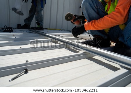 worker wear all safety suit insatlling metal frame on rooftop stock photo